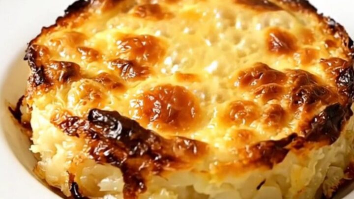 A steaming, golden Savoyard crozet gratin served on a plain white plate, showing a creamy and rich texture.