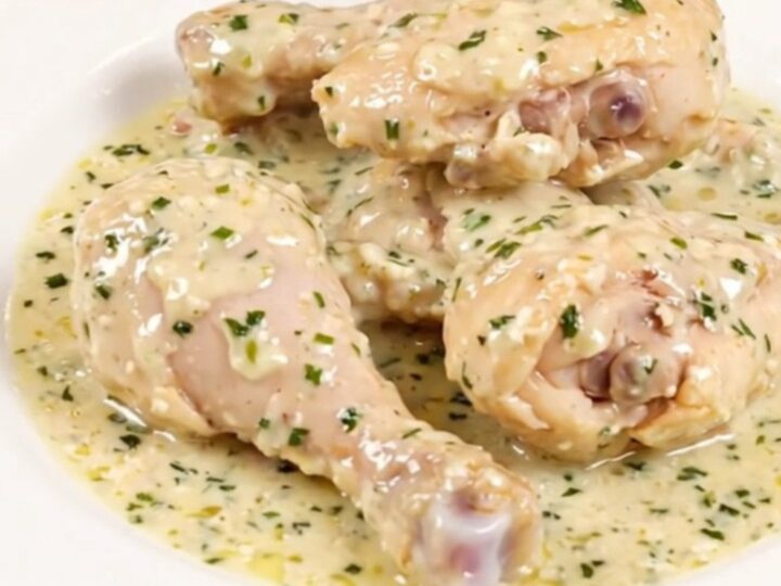 A close-up of creamy garlic and herb slow cooker chicken served on a white plate.