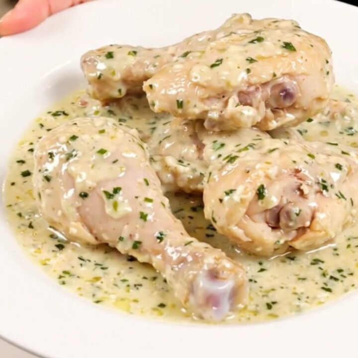 A close-up of creamy garlic and herb slow cooker chicken served on a white plate.