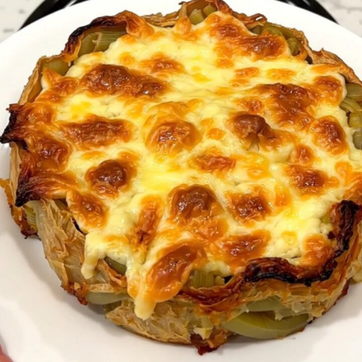 A close-up of a finished slow cooker tartiflette with golden melted cheese and bacon.