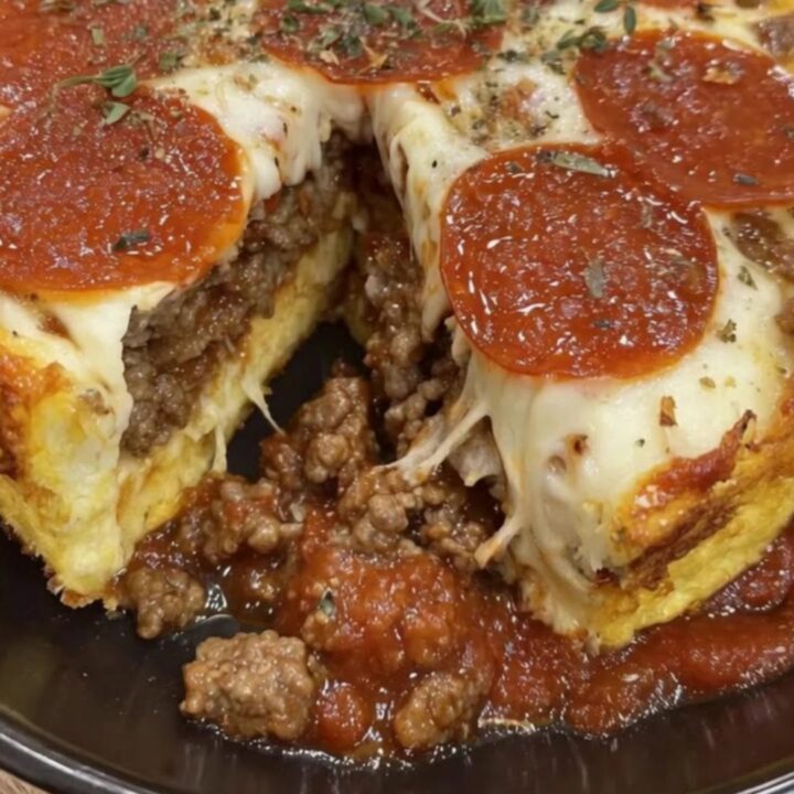 A warm deep-dish impossible pizza pie in a black pan with a slice pulled away displaying stretchy cheese.