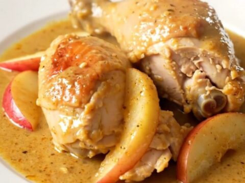 A rustic slow cooker Normandy apple chicken dish served on a white plate with creamy sauce.