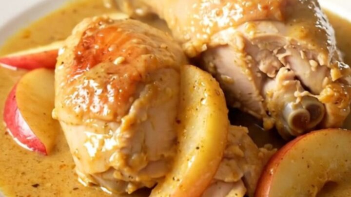 A rustic slow cooker Normandy apple chicken dish served on a white plate with creamy sauce.