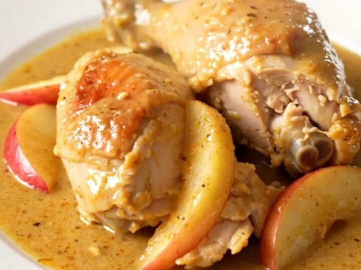 A rustic slow cooker Normandy apple chicken dish served on a white plate with creamy sauce.