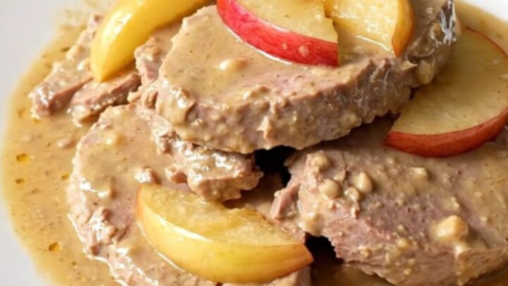 A plate of tender slow-cooked veal chunks served with apple wedges and a glossy cider sauce.