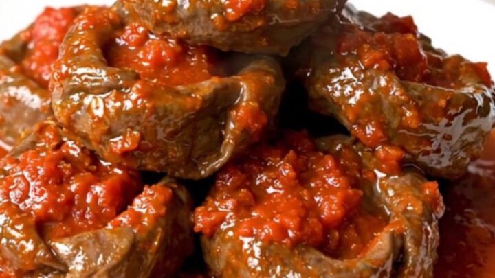 A close-up of tender veal paupiettes cooked in a rich, glossy tomato and herb sauce inside a slow cooker.
