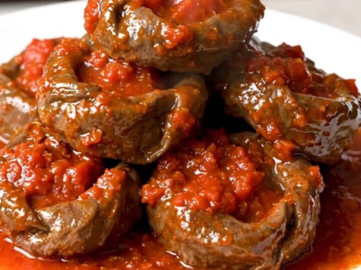 A close-up of tender veal paupiettes cooked in a rich, glossy tomato and herb sauce inside a slow cooker.