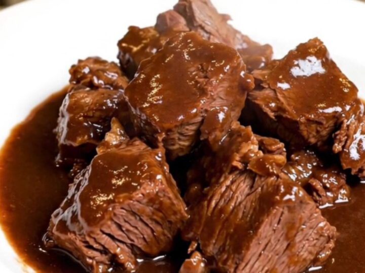 A rustic bowl of slow-cooked beef daube with carrots and mushrooms in a deep red wine sauce.