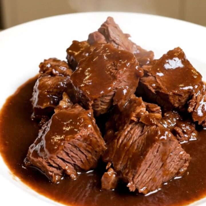 A rustic bowl of slow-cooked beef daube with carrots and mushrooms in a deep red wine sauce.