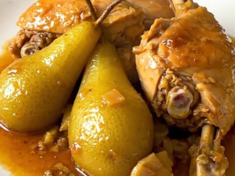 A rustic bowl of slow-cooked chicken drumsticks glazed with honey and tender pear slices.