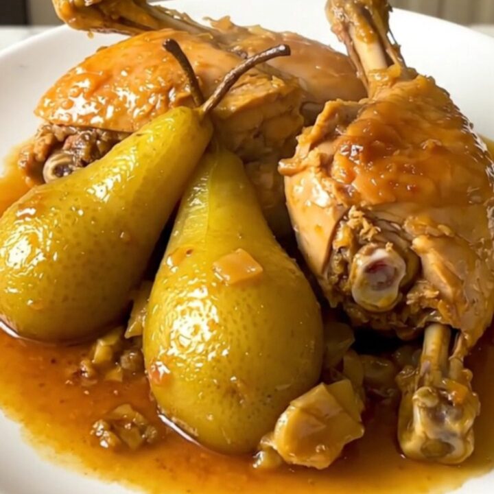 A rustic bowl of slow-cooked chicken drumsticks glazed with honey and tender pear slices.