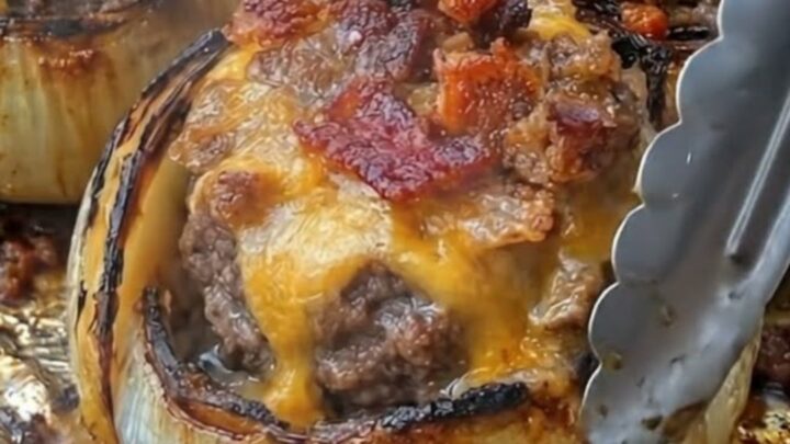 A close-up view of roasted stuffed onions with bubbling melted cheddar and crispy bacon.