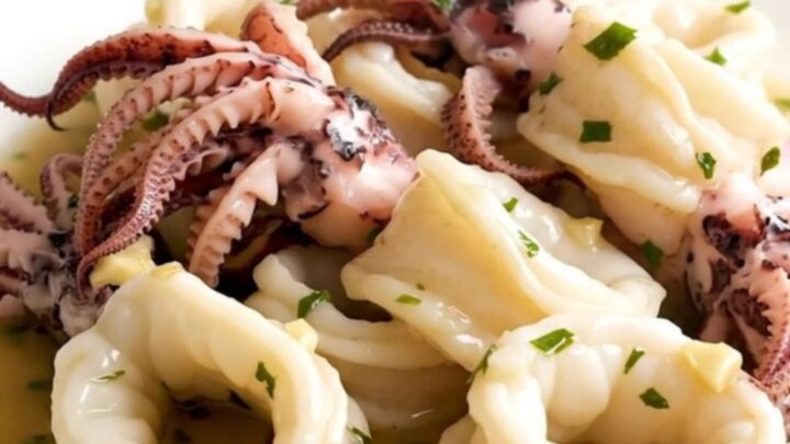A top-down view of raw squid, sliced onions, and garlic in a black slow cooker on a white quartz countertop.