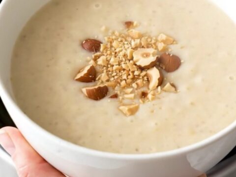 A bowl of velvety, creamy artichoke and potato soup garnished with crushed hazelnuts.