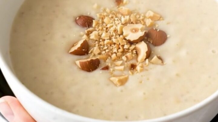 A bowl of velvety, creamy artichoke and potato soup garnished with crushed hazelnuts.
