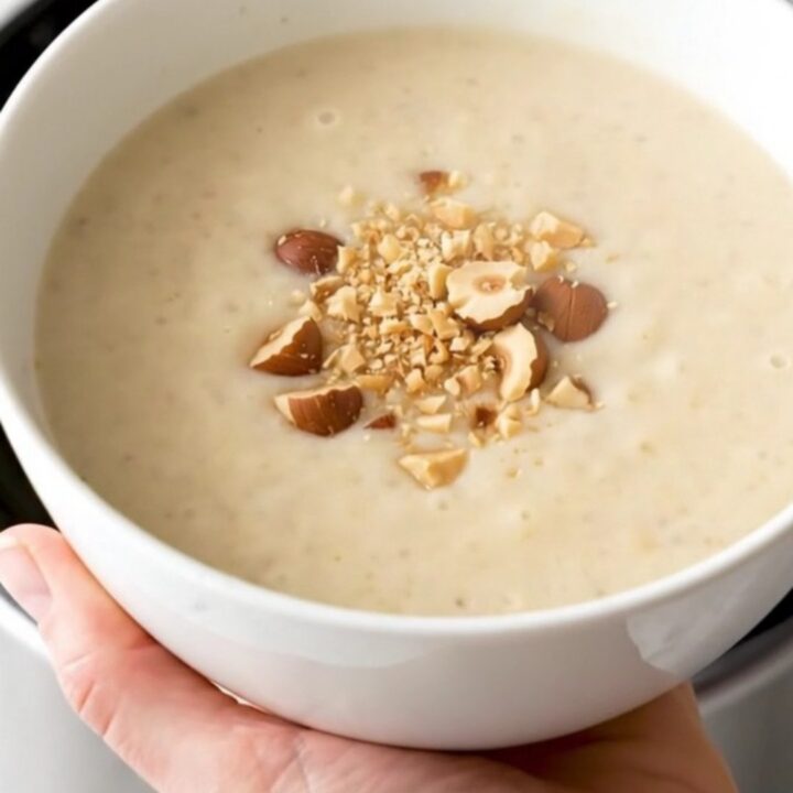 A bowl of velvety, creamy artichoke and potato soup garnished with crushed hazelnuts.