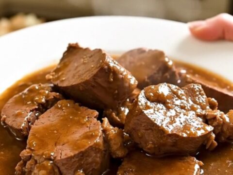 A rustic slow cooker filled with tender veal chunks, pancetta, and fresh rosemary in a rich wine sauce.