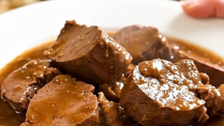 A rustic slow cooker filled with tender veal chunks, pancetta, and fresh rosemary in a rich wine sauce.