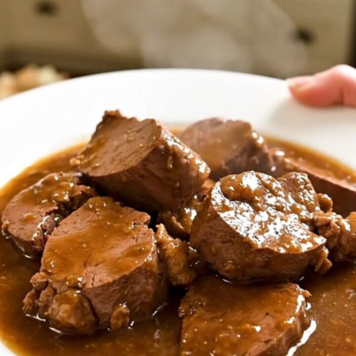 A rustic slow cooker filled with tender veal chunks, pancetta, and fresh rosemary in a rich wine sauce.