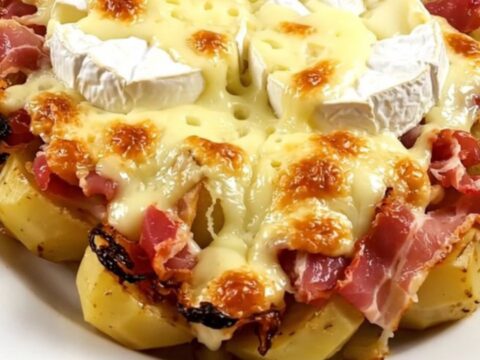 A top-down view of a slow cooker filled with bacon, potatoes, and two wheels of Camembert.