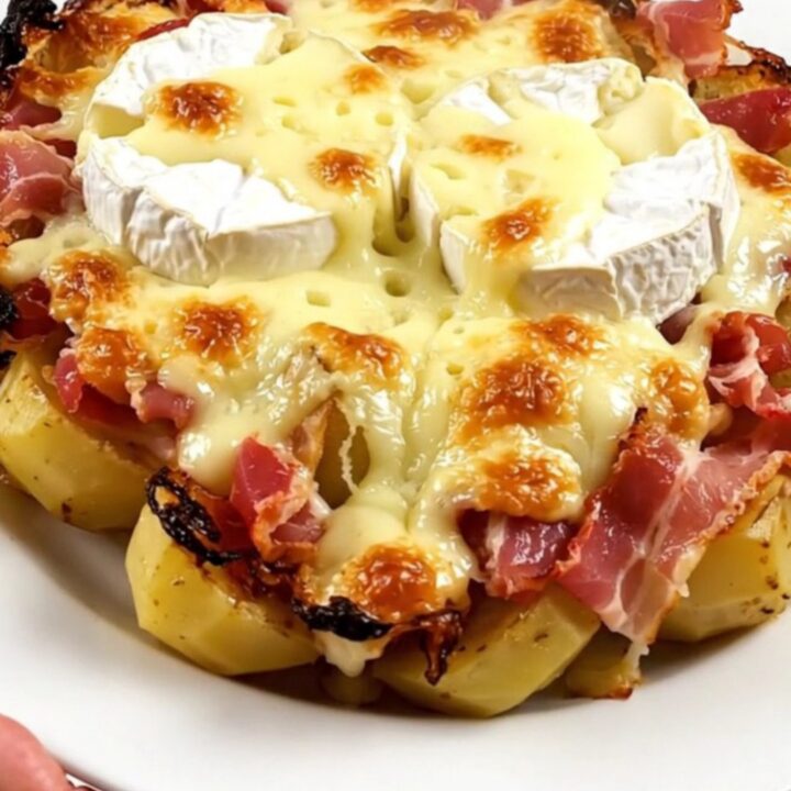 A top-down view of a slow cooker filled with bacon, potatoes, and two wheels of Camembert.