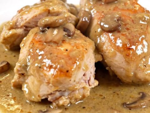 A close-up of creamy porcini chicken served on a white plate with a rich, glossy mushroom sauce.