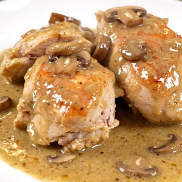 A close-up of creamy porcini chicken served on a white plate with a rich, glossy mushroom sauce.