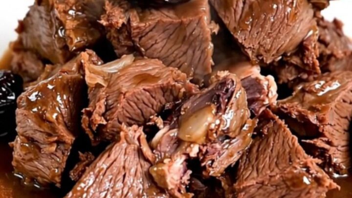A bowl of slow-cooked beef chunks with glossy red wine sauce and plump prunes.