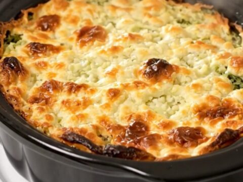 A rustic slow cooker filled with creamy, cooked Swiss chard topped with a dollop of crème fraîche.