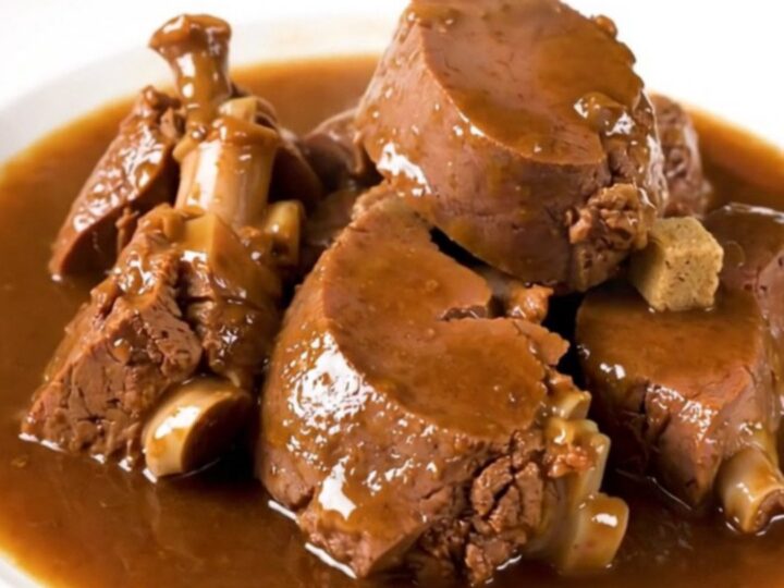 A rustic slow cooker filled with tender veal stew, potatoes, and onions in a rich, glossy broth.