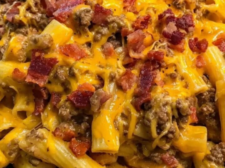 A steaming bowl of creamy rigatoni pasta mixed with browned beef, crispy bacon bits, and molten cheddar cheese.
