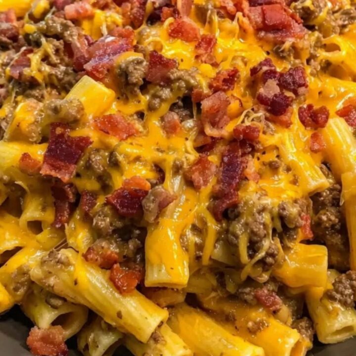 A steaming bowl of creamy rigatoni pasta mixed with browned beef, crispy bacon bits, and molten cheddar cheese.