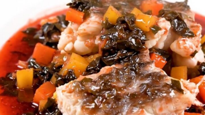 A top-down view of a slow cooker filled with white fish, mushrooms, and pearl onions in a rich red wine sauce.