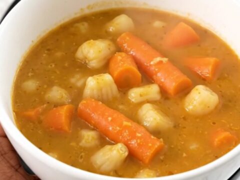 A white bowl filled with creamy slow-cooked sunchoke and carrot stew, garnished with fresh tarragon.