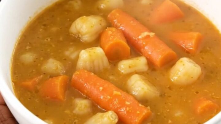 A white bowl filled with creamy slow-cooked sunchoke and carrot stew, garnished with fresh tarragon.