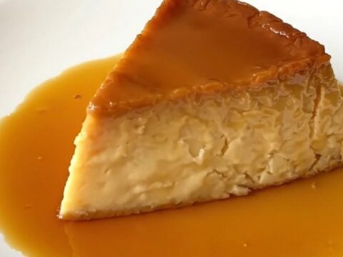 A slice of glossy, firm vanilla and orange blossom flan on a white plate.