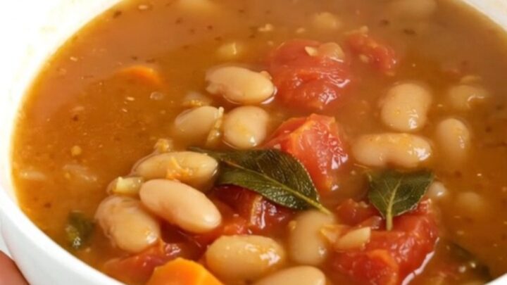 A steaming white bowl filled with white bean, tomato, and sage soup