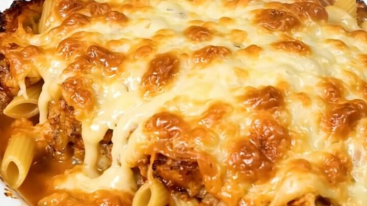 A top-down view of a steaming tuna and emmental pasta bake in a black slow cooker on a speckled countertop.