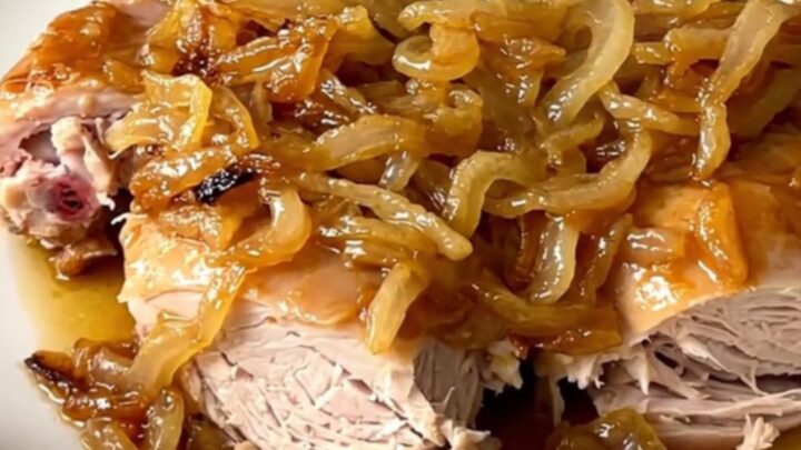 A close-up view of slow cooker turkey yassa served on a white plate with tender onions and a savory sauce.
