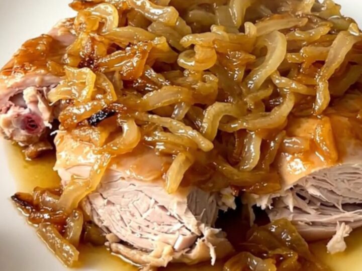 A close-up view of slow cooker turkey yassa served on a white plate with tender onions and a savory sauce.