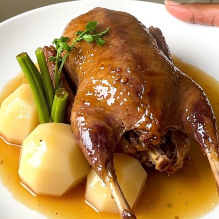 A close-up of slow-cooked guinea fowl and turnips in a glossy honey glaze on a white plate.