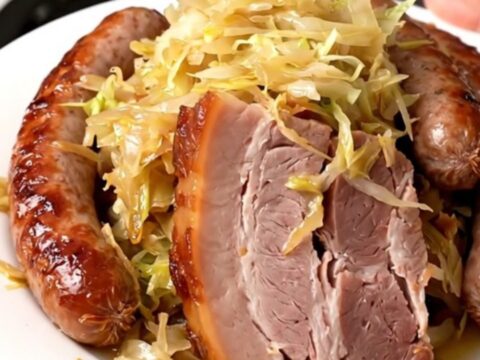 A top-down view of a slow cooker filled with smoked pork belly, sauerkraut, juniper berries, and champagne.