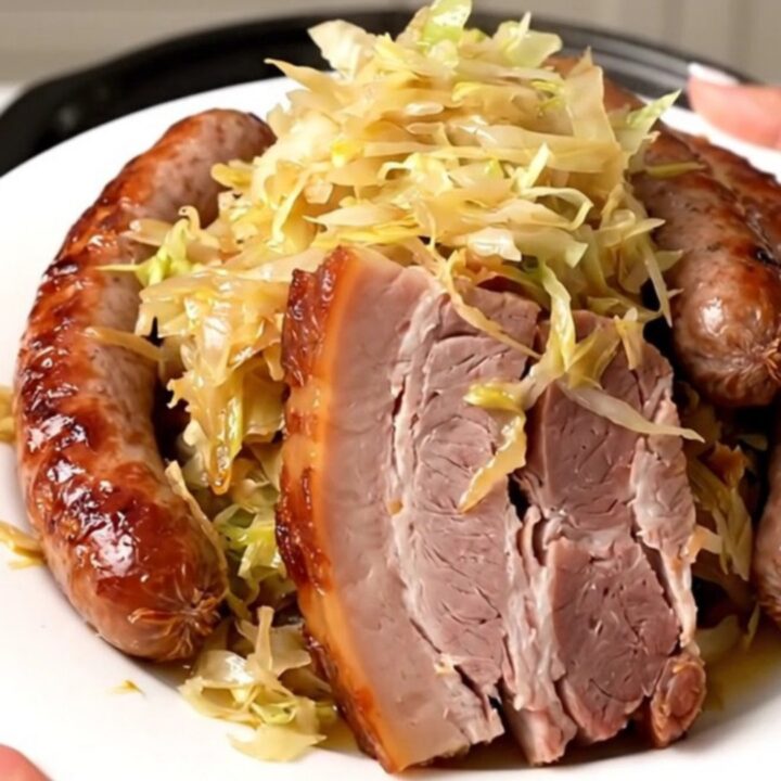 A top-down view of a slow cooker filled with smoked pork belly, sauerkraut, juniper berries, and champagne.