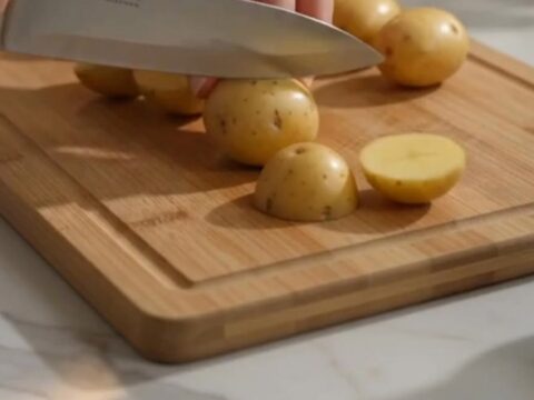 A bowl of glistening, golden-brown garlic potatoes garnished with grated parmesan cheese and fresh parsley.