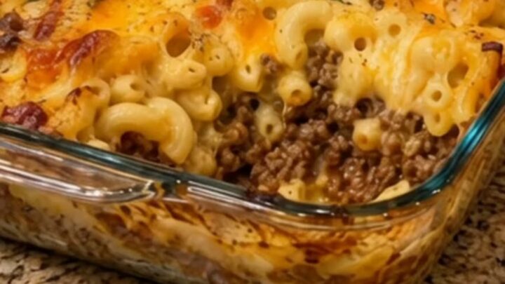 A steaming portion of baked macaroni and cheese with ground beef being lifted by a spatula.