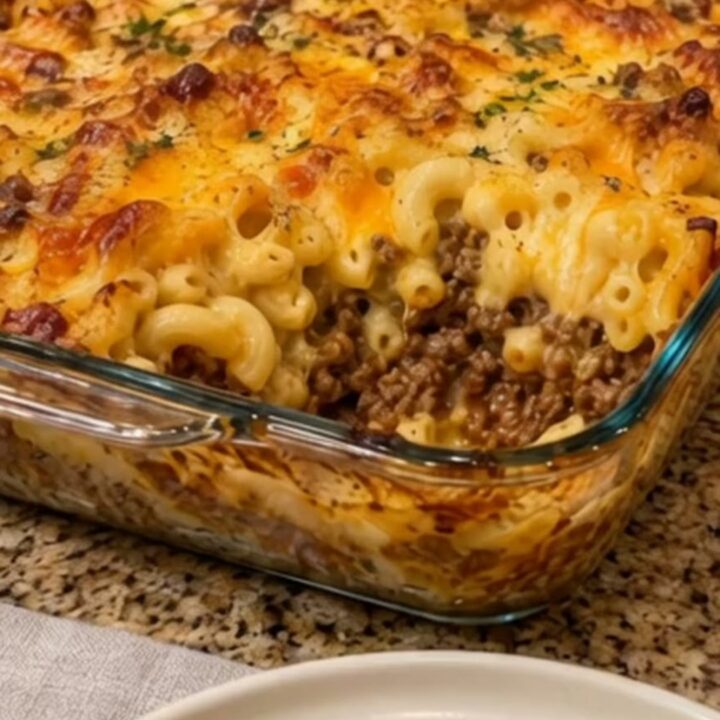 A steaming portion of baked macaroni and cheese with ground beef being lifted by a spatula.