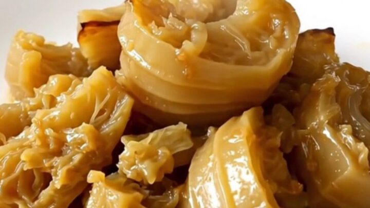 A close-up of tender, braised celeriac cubes served on a white plate with fresh thyme.