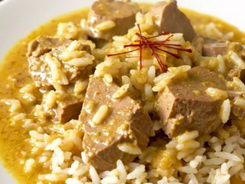 Slow cooker saffron veal blanquette served on a white plate with steamed rice.