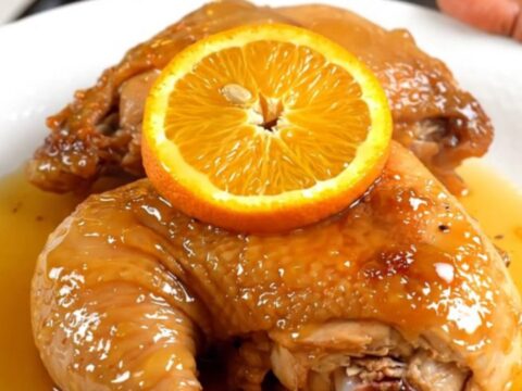 A close-up of tender orange rosemary chicken in a slow cooker with fresh citrus slices.