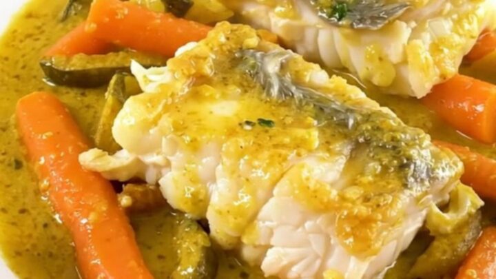 A top-down view of raw haddock fillets, sliced carrots, and onions in a slow cooker.
